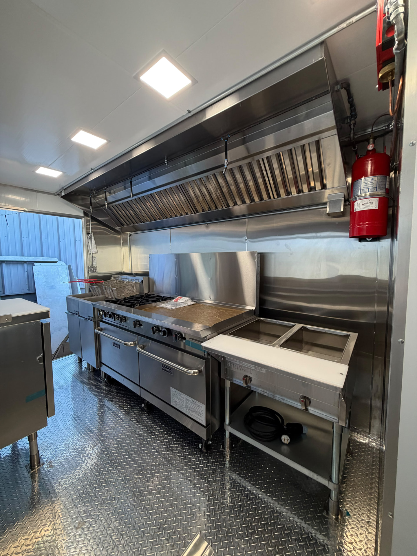 Cooking line with fryers, range with griddle, steam table, exhaust hood and fire suppression